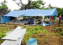 津波で破壊された集落の住民が仮の住まいで生活している