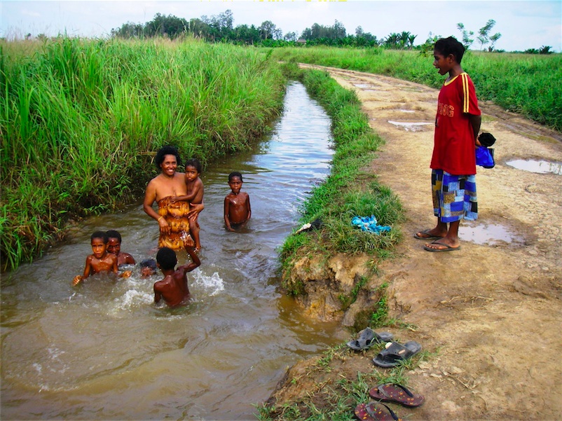 04.濁った水路で水浴びをする女性と子どもたち（プロジェクト前）
